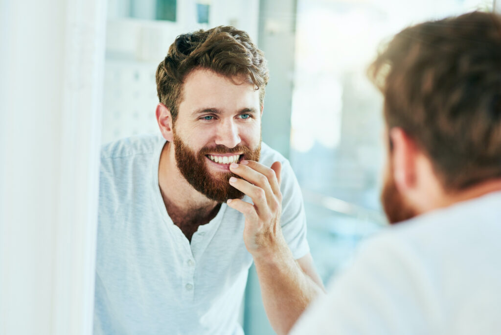 man looking at new smile in the mirror
