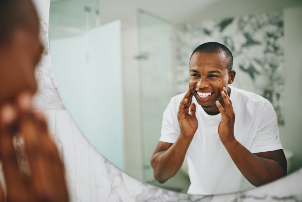 A man looking in the mirror who straightened his teeth without braces